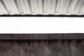 Geometric industrial dark composition of a concrete gray wall and an iron corrugated roof of a building