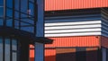 Aluminium louver of orange metal warehouse near modern office industrial building with sunlight and shadow on surface