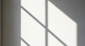 Geometric pattern of light and shadow on a plain wall, likely from a window with multiple panes. Royalty Free Stock Photo