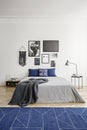 Pattern on a navy blue rug and framed photo gallery on a white wall in an eclectic bedroom interior