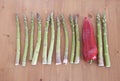 geometric pattern of stalks of green asparagus and one red paprika on a wooden