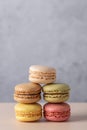 Geometric stack of French macarons in pink, yellow, green, beige and brown on beige surface with gray background. Royalty Free Stock Photo