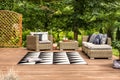 Geometrical rug and rattan furniture set on a terrace in a garden full of trees