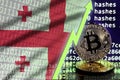 Georgia flag and rising green arrow on bitcoin mining screen and two physical golden bitcoins