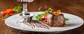 Georgian cuisine. Juicy beef steak, veal steak on a white plate with roasted rocket, grilled vegetables and sauce Royalty Free Stock Photo