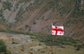 Georgian Flag Waving Against the Valley of Stepantsminda, Khevi province, Georgia Royalty Free Stock Photo