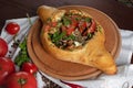 Georgian khachapuri with meat and tomatoes on a round kitchen board