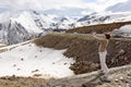 Georgian Military Road, GE-May,3 2019:Young woman taking pictures of exciting view of Snow-capped peaks of Caucasus Mountains.