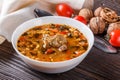 Georgian soup. Kharcho with rice, tomato, beef, garlic and herbs in bowl on wooden table