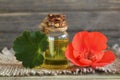 Geranium essential oil in a glass bottle with flower and leaves of the geraniums plant on wooden table. Royalty Free Stock Photo