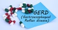 GERD word on a blue sheet of paper against the background of multicolored tablets