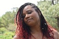 A portrait of a radiant and spectacular woman of color with a rare, braided hair style of red dye at the ends