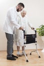 Geriatric doctor teaches to walk an old woman using a rehabilitation walker. Royalty Free Stock Photo