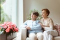 Geriatric woman and her professional caretaker sitting on a couc