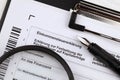 German annual income tax return declaration form blank on A4 tablet lies on office table with pen and magnifying glass