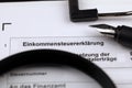 German annual income tax return declaration form blank on A4 tablet lies on office table with pen and magnifying glass