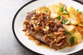 German beef steak Rostbraten with onion and fried potatoes closeup on the plate. Horizontal Royalty Free Stock Photo