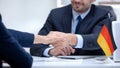 German boss signing employment contract with immigrant employee, shaking hand Royalty Free Stock Photo