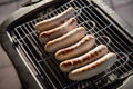 German Bratwurst pork sausage on electric barbecue BBQ grill Royalty Free Stock Photo