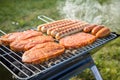 German Bratwurst sausages and marinated pork neck steak meat roasting with smoke on foldable charcoal BBQ barbecue grill in garden Royalty Free Stock Photo