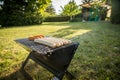 German Bratwurst sausages of pork meat roasting on foldable charcoal BBQ barbecue grill in garden on summer evening Royalty Free Stock Photo