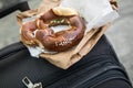 German Brezel pretzel with chives, butter and cream cheese on bakery bag and suitcase as snack on the go during travelling