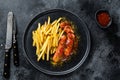 German currywurst Sausages with French fries on a plate. Black background. Top view