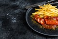 German currywurst Sausages with French fries on a plate. Black background. Top view. Copy space Royalty Free Stock Photo