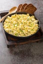 German egg salad with apples and pickles dressed with mayonnaise close-up in a bowl. Vertical