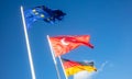 German, EU, Turkey waving flags on white poles. Blue sky background