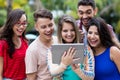 German female student with tablet computer and group of cheering students Royalty Free Stock Photo