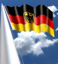 German flag waved by the wind with silky appearance with the shield of the German eagle with a background of blue sky with white c Royalty Free Stock Photo