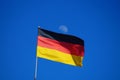 The German flag flying against a blue sky with the moon in the background Royalty Free Stock Photo