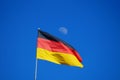 The German flag flying against a blue sky with the moon in the background Royalty Free Stock Photo