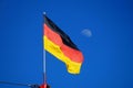 The German flag flying against a blue sky with the moon in the background Royalty Free Stock Photo