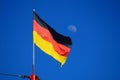 The German flag flying against a blue sky with the moon in the background Royalty Free Stock Photo