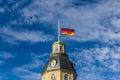 German Flag at Halfmast, auf Halbmast, on the tower roof of Castle Karlsruhe, blue sky behind. In Baden-WÃÂ¼rttemberg, Germany Royalty Free Stock Photo