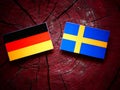 German flag with Swedish flag on a tree stump Royalty Free Stock Photo