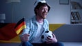 German football fan enthusiastic watching game on sofa, supporting national team