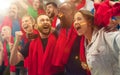 German football, soccer fans cheering their team with a red scarfs at stadium. Excited fans cheering a goal, supporting