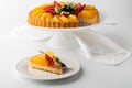 German fruit flan with one slice on a plate in front ready for eating.