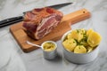 German Kassler pork neck with boiled potatoes and mustard on marble table