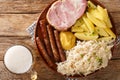German Kassler pork neck with Sauerkraut potatoes and mustard on wooden table closeup. Horizontal top view