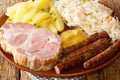 German Kassler pork neck with Sauerkraut potatoes and mustard on wooden table closeup in the plate. Horizontal