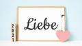 German Liebe words and 2021 cubes with red heart shape decoration on blue wooden table background. New Year NewYou, Goal, Royalty Free Stock Photo