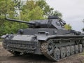 German medium tank of the Second World war in working order. the tank is painted black against a background of green trees in summ