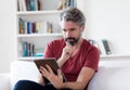 German middle aged man with grey hair reading e-book with digital tablet