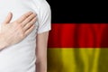 German person with hand on heart on the background of Germany flag. Patriotism, country, national, pride concept Royalty Free Stock Photo