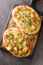 German pizza Swabian Dinnete with potatoes, onions and bacon close-up on a wooden board. vertical top view