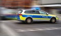 German police emergency vehicle with blue lights on speeds through an intersection, intentional motion blur of background Royalty Free Stock Photo